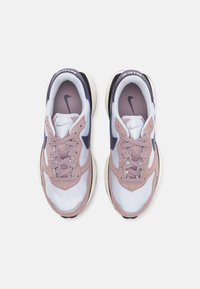 Nike-sneakers med en vit mesh-oversida, rosa mockadetaljer, lila inslag och en svart sula; har snören och en logotyp på tungan.