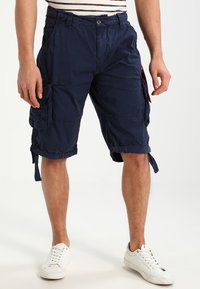 Marine cargo shorts laget av stoff med avslappet passform, med sidelommer, justerbare mansjetter og knappestolpe. Stylet med en stripete topp.