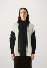Maglione a collo alto in stile loose-fit, nero e crema, con strisce verticali, dettagli a trecce e orlo e polsini a coste.
