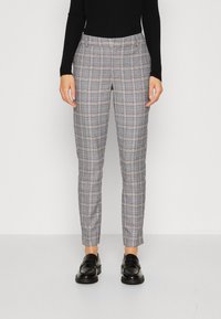 Šedé kostkované kalhoty z tkané látky, úzkého střihu, s předními kapsami a jemným leskem, v kombinaci s černými mokasíny.