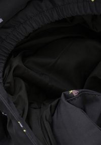 Intérieur en tissu noir d'un sac, doté d'une texture lisse, d'une ouverture élastiquée et de accents subtils à motifs dans des couleurs claires.