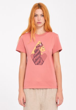 T-shirt en coton rose à manches courtes avec un graphisme représentant le profil d'une lionne à l'intérieur d'une forme de diamant.