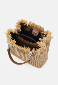 Torebka w kolorze tan i kremowym, pleciona, z frędzlami na górze, brązowymi skórzanymi akcentami, srebrnym okuciem oraz przestronnym wnętrzem z kieszeniami.