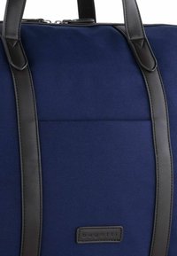 Tote aus marineblauem Stoff mit schwarzen Ledergriffen und Akzenten. Verfügt über ein schlichtes Design und eine rechteckige Form mit einem Logopatch.