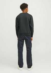 Felpa nera con collo a giro, polsini e orlo a costine, abbinata a pantaloni cargo blu navy con tasche laterali e vestibilità morbida.