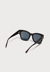 Ochelari de soare din scoică cu lentile închise, cadru unghiular și accente din aur. Material plastic robust cu textură netedă.