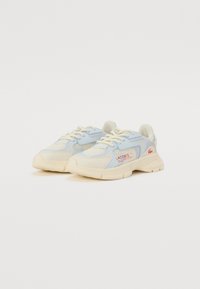 Baskets Lacoste avec une tige en mesh et cuir bleu clair, des accents crème, une semelle en caoutchouc épaisse et des détails de logo rouge sur le côté.