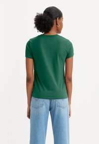 Groene katoenen T-shirt met korte mouwen en een ronde hals, gecombineerd met lichtblauwe hoge taille jeans met achterzakken.
