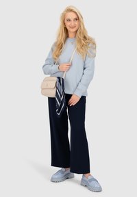 Felpa azzurra, pantaloni larghi blu navy, scarpe con piattaforma azzurre, borsa a tracolla beige con un accessorio a sciarpa a righe blu navy.