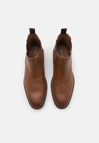 Bottines en cuir marron avec une texture lisse, des panneaux latéraux élastiques et des tirettes pour un enfilage facile ; bout arrondi et détail de couture contrastante.