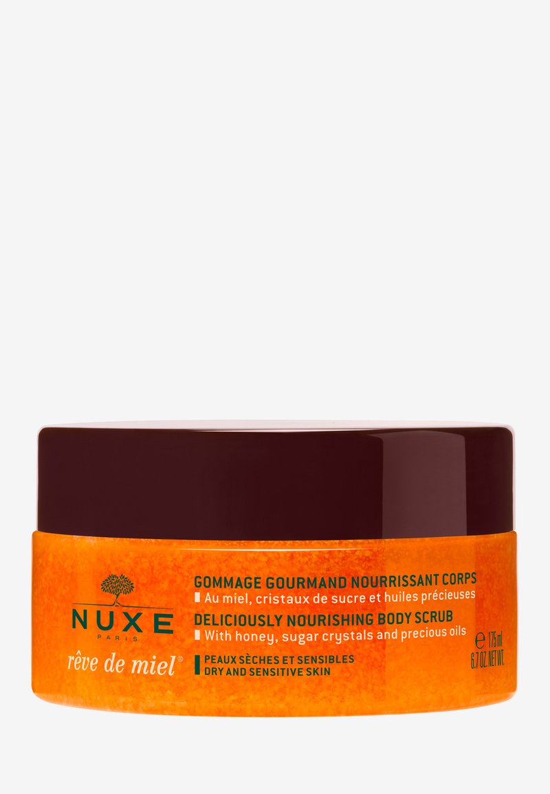 Orangenes Glas mit einem dunkelbraunen Deckel, beschriftet mit "Nuxe Rêve de Miel" Körperpeeling. Die Hauptbestandteile sind Honig und Zuckerkristalle. 175 ml Kapazität.