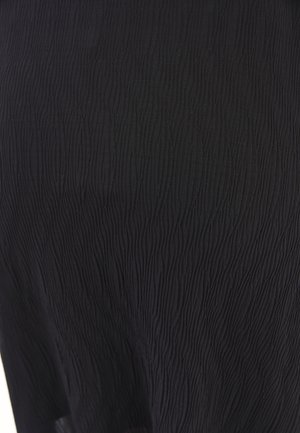 Tessuto nero testurizzato con un motivo ondulato, che mostra un materiale leggero e elastico. Messa a fuoco ravvicinata sui dettagli della superficie e sulla lucentezza.