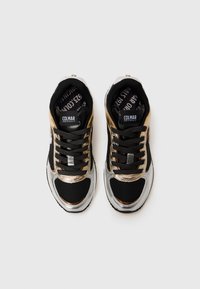 Schwarze Sneakers mit metallischen Silber- und Goldakzenten, ausgestattet mit einer strukturierten Oberseite, runden Schnürsenkeln und einer gepolsterten Zunge mit der Aufschrift "Colmar Originals."