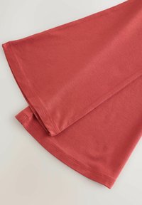 Material roșu drapat în două secțiuni, cu o textură moale și un design simplu, neted, cu tivuri finisate și fără modele sau accente vizibile.