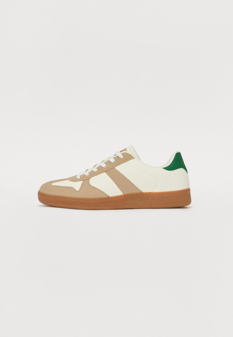 Sneakers med en overdels i hvid læder, overlag i tan ruskind, grøn hælakkent og en struktureret gummisål. Har tre striber i tan.