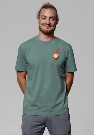 Groene katoenen t-shirt met een gnome grafiek met een rode hoed, blauwe shirt en gereedschap, ontworpen met een ronde hals en korte mouwen.