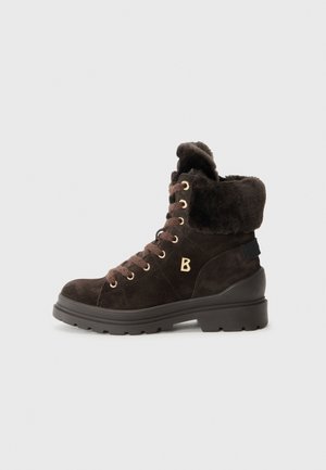 Bottine en suede marron avec doublure en fourrure, œillets dorés et semelle noire épaisse. Affiche un logo 'B' sur le côté.