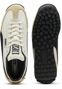 Sportieve schoenen met een crème leren bovenkant, beige suède accenten, zwarte zijpanelen en een gestructureerde zwarte rubberen zool met ronde grip.