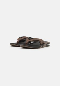Brune flip-flops med strukturerte stropper, svart fotbrett og fleksibel såle. Har en liten logo på stroppen og mønstret såle på bunnen.