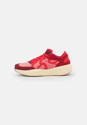 Rode en roze sportschoen met gestructureerde stof en dikke off-white zool, zijaanzicht op een effen witte achtergrond.