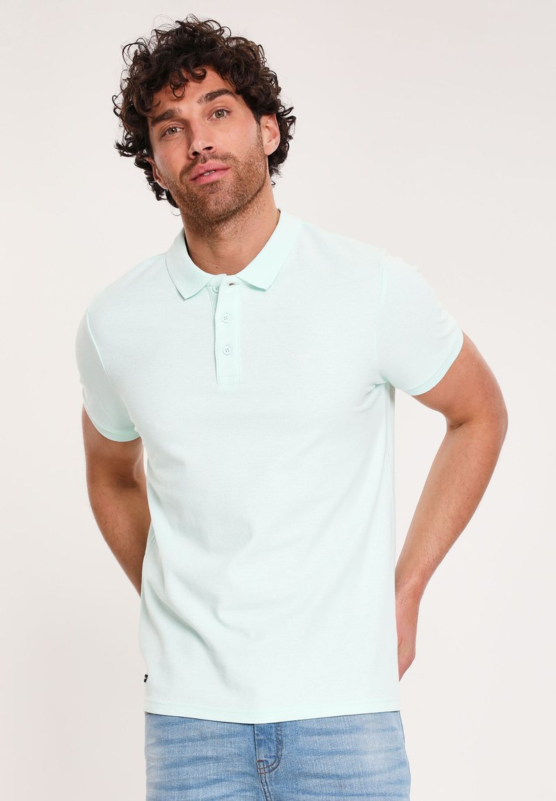 Lyse mintgrøn polo-shirt med krave, korte ærmer og en tre-knaps lukning; tekstureret stof med en subtil logo accent.