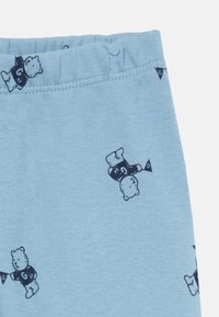 Ljust blå bomullsleggings med en mjuk textur, som har ett upprepande mönster av svarta tecknade björnar och ett elastiskt midjeband.