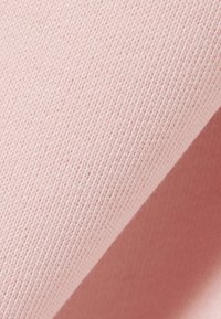 Gros plan sur un tissu tricoté rose pâle montrant un motif de points détaillé et une texture douce.