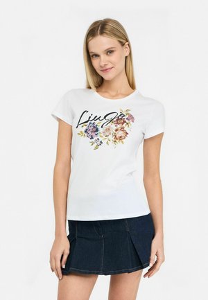 T-shirt en coton blanc avec un imprimé floral en rose, bleu et jaune, portant le nom de la marque "Liu Jo" écrit sur le devant.