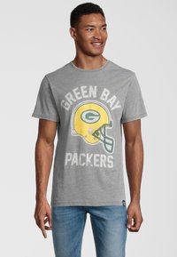 Harmaa puuvillapaita, jossa on Green Bay Packers -logo keltaisella kypärällä, rohkealla valkoisella tekstillä ja klassisella pyöreällä kaula-aukolla.