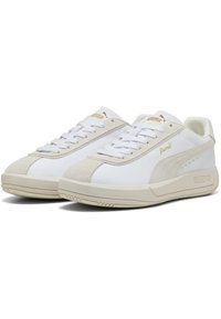 Vita sneakers med mockadetaljer, med en tjock, ljusfärgad sula och framträdande snörning. Guldlogotypdetaljer på sidorna och på plösen.