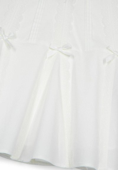 Tissu blanc avec des plis horizontaux et une bordure en dentelle. Présente de petits nœuds à intervalles. Texture douce et design fluide.