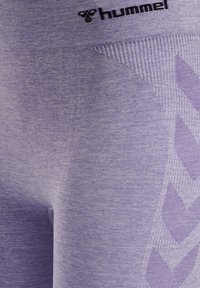 Paarse sportlegging met een geribde tailleband, met een zigzagpatroon aan de zijkant, gemaakt van een zachte, gestructureerde stof.