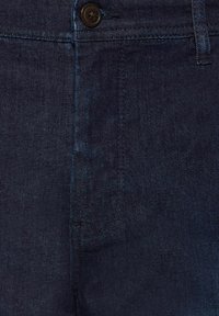 Jeans en denim foncé avec une texture lisse, un motif en twill subtil et une fermeture à un bouton à la taille.