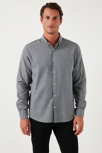 Grijze lange mouwknopshirt gemaakt van gestructureerde stof, met een kraag, knopen aan de voorkant en een licht gebogen zoom. Gecombineerd met zwarte broek.