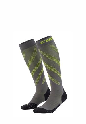 Graue Kniestrümpfe mit Kompression, verziert mit neongrünen diagonalen Streifen sowie schwarzen Fersen- und Zehenbereichen. "CEP" Logo nahe der oberen Bündchenkante.
