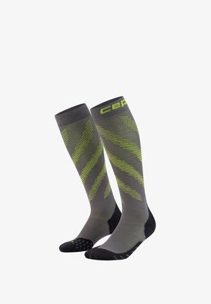 Graue Kniestrümpfe mit Kompression, verziert mit neongrünen diagonalen Streifen sowie schwarzen Fersen- und Zehenbereichen. "CEP" Logo nahe der oberen Bündchenkante.