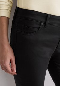 Zwarte jeans met een slim fit, gemaakt van een zachte katoenen mix, voorzien van voorzakken en een gladde textuur. Gestikte naden zijn zichtbaar.