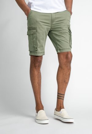 Groene cargoshorts van katoen, met zijzakken, een knielange snit en contrasterende stiksels. Gemaakt in combinatie met witte instappers.