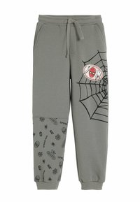 Graue Jogginghosen mit einem Kordelzug, die ein Spinnennetzdesign und ein Spider-Man-Patch an einem Bein aufweisen, während das andere Bein verschiedene Spinnenmotive zeigt.