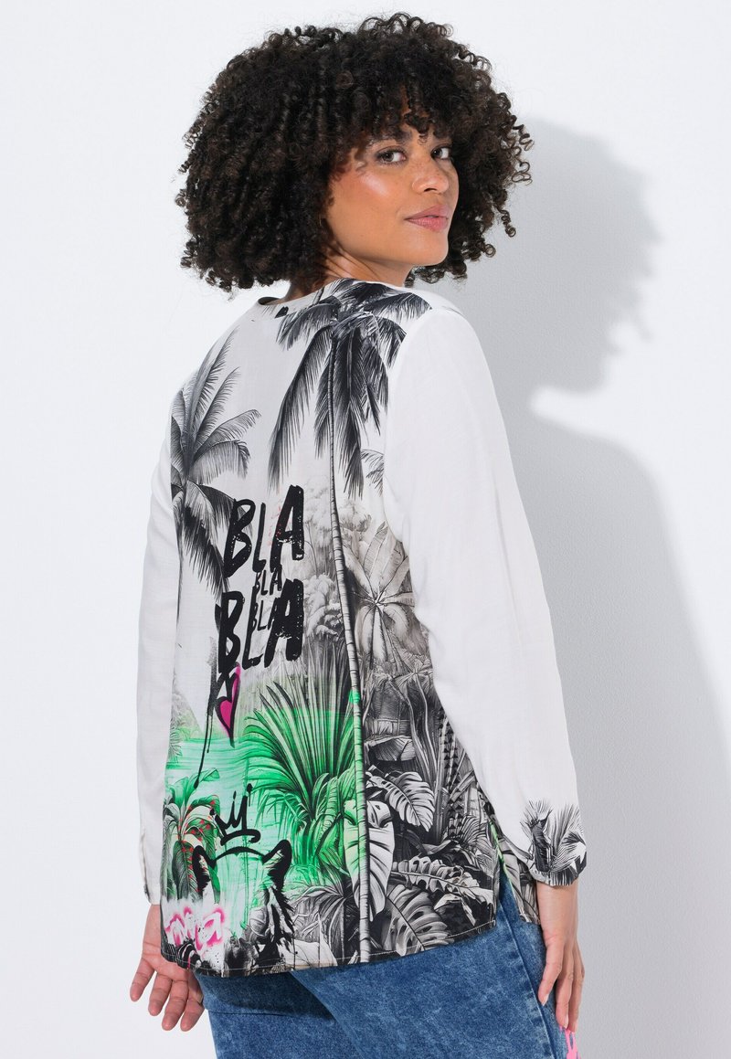 Langearm shirt met een zwart-wit tropenprint op de achterzijde, voorzien van kleurrijke graffiti-accenten en een relaxte pasvorm. Witte voorkant.