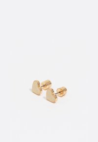 Un par de pendientes de studs en forma de corazón dorados con postes metálicos y el nombre de la marca grabado en la parte delantera y trasera.