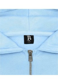 Light blue zip-up hoodie with a fleece-lined interior, featuring a silver zipper and a black label with a stylized "B" and size indication.