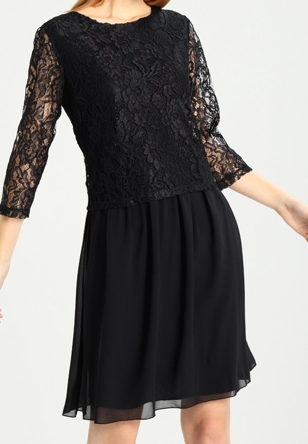 Svart knälång klänning med blommig spetsliv och trekvartsärmar i spets, kombinerad med en svängd chiffongkjol.