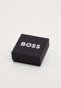 Must švartne ristiklik kast sujuva pinnaga, mille kaanel on silmatorkavalt valge sõna "BOSS".