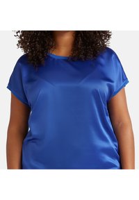 Satijnen blauwe top met korte mouwen, een ronde halslijn en een gladde textuur. Eenvoudig ontwerp zonder patronen of versieringen.