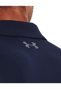 Námornícky polo tričko s textúrovanou látkou a čiernym logom na golieri. Disponuje klasickým dizajnom goliera a elegantným, moderným vzhľadom.