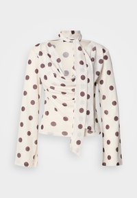 Bluzka z długim rękawem wykonana w kremowej tkaninie w brązowe kropki. Posiada drapowany przód i wiązanie przy szyi. Miękka w dotyku, dopasowany krój.