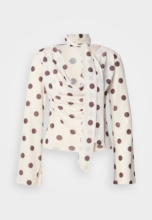 Langärmlige Bluse aus cremefarbenem Stoff mit braunen Polka-Dots. Verfügt über eine drapierte Vorderseite und eine gebundene Nackendetail. Weiche Textur, figurbetontes Design.