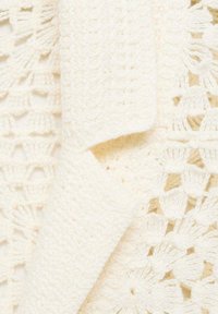 Haakdeken in zachte crème kleur, met een textuur, openwerk ontwerp met bloemenpatronen en een lichte, luchtige uitstraling.