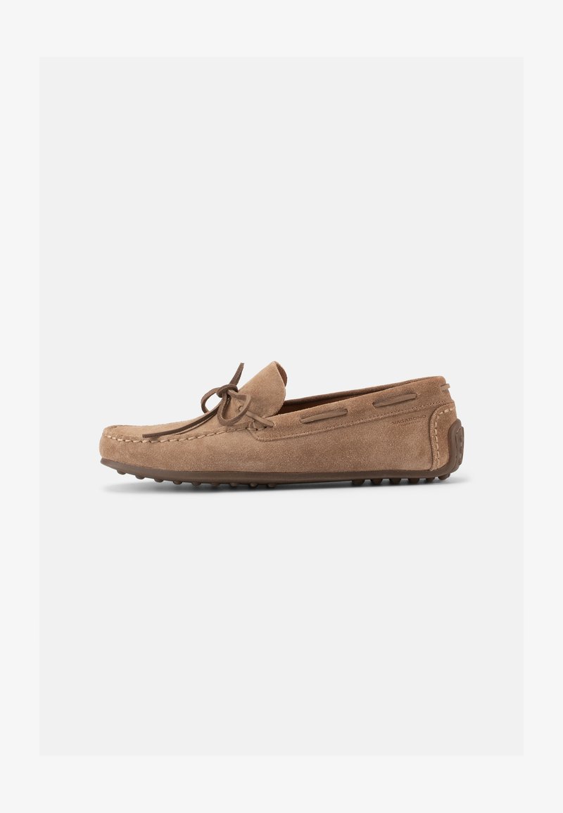 Lichtbruine suède rijloafer met strikdetail, mocassin-teenstiksel en rubberen steentjeszool, zijaanzicht tegen een witte achtergrond.